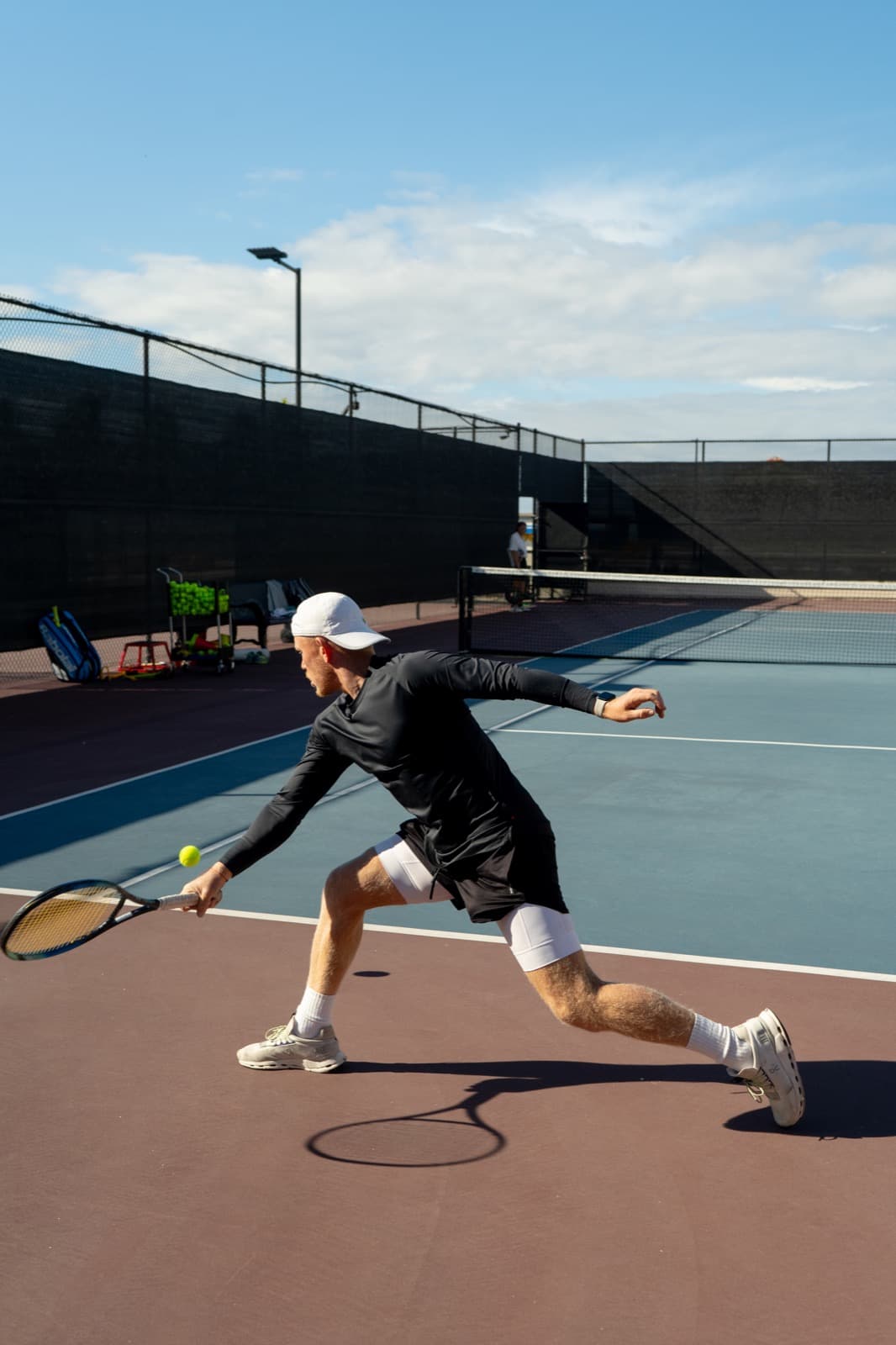 Tennis player lunging for a ball on an outdoor court